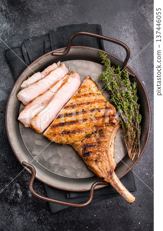 Flavorful grilled pork loin chop with bone, expertly cooked to perfection, making it the star of any meal. black background. top view 137446055