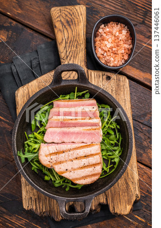 Tender grilled tuna steak on a bed of greens, an exquisite blend of flavors that delights the palate. wooden background. top view Tender grilled tuna steak on a bed of greens, an exquisite blend of flavors that delights the palate. wooden background. top view 137446061