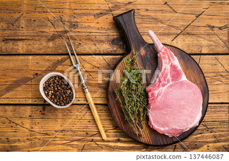 Pristine pork loin chop, featuring a thick cut and beautiful marbling, ideal for a hearty dinner. wooden background. top view Pristine pork loin chop, featuring a thick cut and beautiful marbling, ideal for a hearty dinner. wooden background. top view 137446087