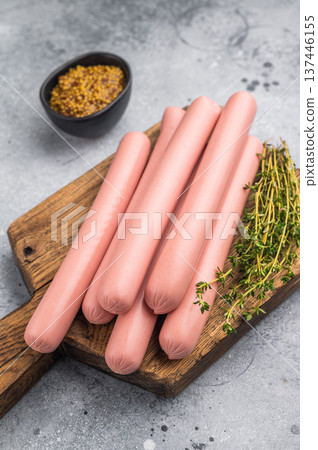 Raw hot dog sausages (frankfurters/wieners) on a cutting board with thyme and mustard on a rustic background. Food preparation concept. Raw hot dog sausages (frankfurters/wieners) on a cutting board with thyme and mustard on a rustic background. Food preparation concept. 137446155