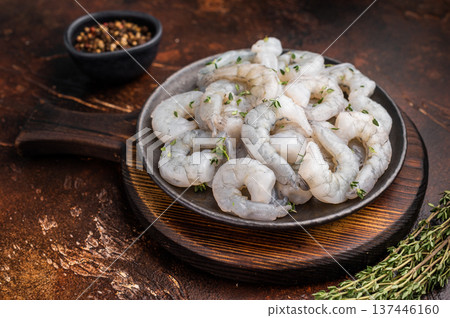 Raw peeled shrimp prawn in a cast iron skillet on a dark rustic wood background. Overhead shot with copy space and spices. 137446160