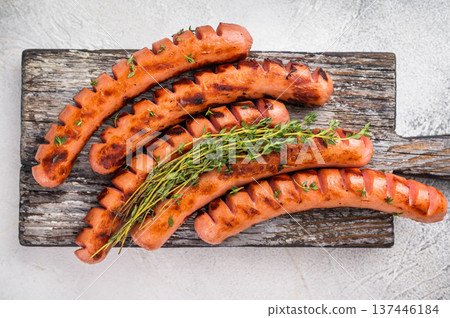 Grilled and cut sausages (wieners/frankfurters) on a rustic wooden board with two types of mustard. Perfect for BBQ menu design. 137446184