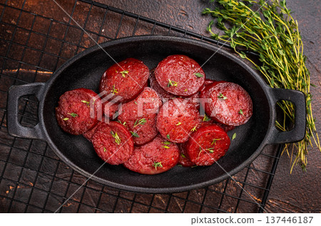 Fried Turkish sucuk (sujuk) slices in a cast iron pan with thyme and spices on a dark rustic wooden table. Fried Turkish sucuk (sujuk) slices in a cast iron pan with thyme and spices on a dark rustic wooden table. 137446187
