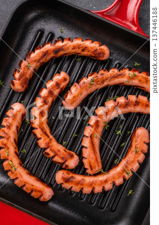 Grilled and cut sausages (wieners/frankfurters) in a hot cast iron grill pan on a dark background. Ready meal concept for dinner or BBQ. 137446188