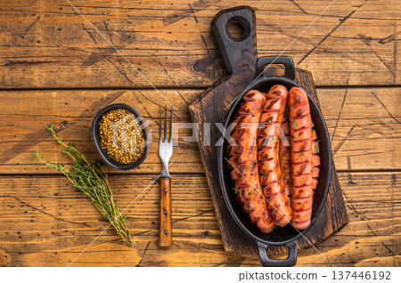 Juicy, smoky fried sausages on a wooden board with herbs and fork. High-quality image for restaurant menus or food blog headers. 137446192
