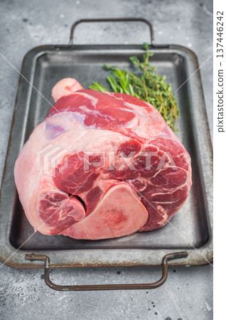 Raw beef shank with bone in metal tray with rosemary thyme and pink salt uncooked meat on light background for osso buco Raw beef shank with bone in metal tray with rosemary thyme and pink salt uncooked meat on light background for osso buco 137446242