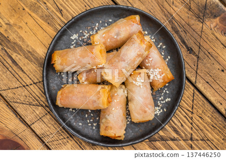 Crispy fried Egg rolls with sesame seeds on dark ceramic plate rustic wooden background top view Crispy fried Egg rolls with sesame seeds on dark ceramic plate rustic wooden background top view 137446250