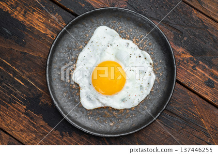 Rustic breakfast scene with hot fried egg on ceramic plate, rich wood texture and balanced overhead composition for food layouts. Rustic breakfast scene with hot fried egg on ceramic plate, rich wood texture and balanced overhead composition for food layouts. 137446255
