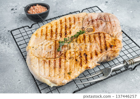 Grilled bone in pork shoulder with herbs on cooling rack cooked meat with grill marks prepared for barbecue and rustic serving Grilled bone in pork shoulder with herbs on cooling rack cooked meat with grill marks prepared for barbecue and rustic serving 137446257