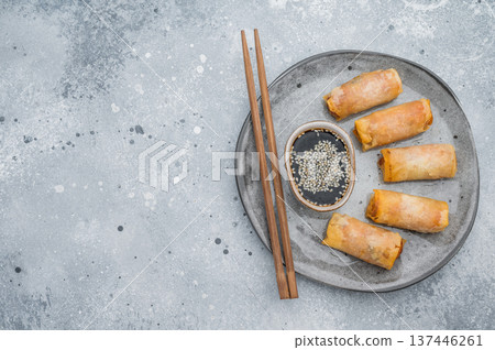 Crispy fried spring rolls served with soy dipping sauce and sesame seeds Asian appetizer flat lay on stone background Crispy fried spring rolls served with soy dipping sauce and sesame seeds Asian appetizer flat lay on stone background 137446261
