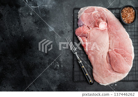 Raw bone in pork shoulder on cooling rack over dark background fresh marbled meat with salt for barbecue smoking roasting and slow cook Raw bone in pork shoulder on cooling rack over dark background fresh marbled meat with salt for barbecue smoking roasting and slow cook 137446262