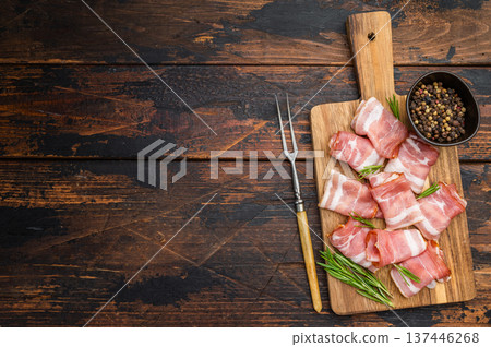 Rolled raw bacon pork rashers on rustic wooden board with rosemary and pepper ideal for cooking recipes and food styling content Rolled raw bacon pork rashers on rustic wooden board with rosemary and pepper ideal for cooking recipes and food styling content 137446268