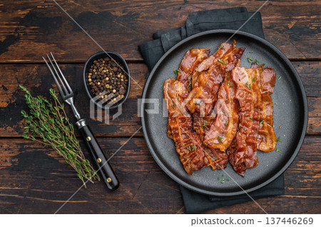 Crispy fried bacon arranged on a black plate over rustic wood offering deep color, shine and high-impact gourmet atmosphere. Crispy fried bacon arranged on a black plate over rustic wood offering deep color, shine and high-impact gourmet atmosphere. 137446269