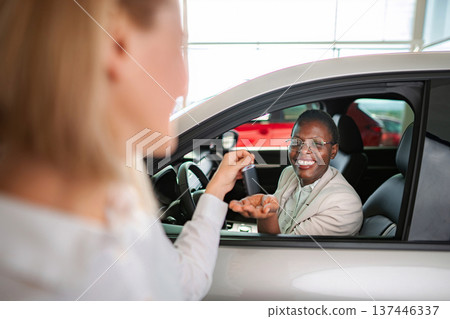 Woman receiving new car key at dealership Woman receiving new car key at dealership 137446337