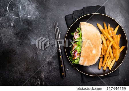 Turkish Shawarma, Doner kebab with grilled chicken meat in pita bread on a plate with french fry. black background. top view Turkish Shawarma, Doner kebab with grilled chicken meat in pita bread on a plate with french fry. black background. top view 137446369