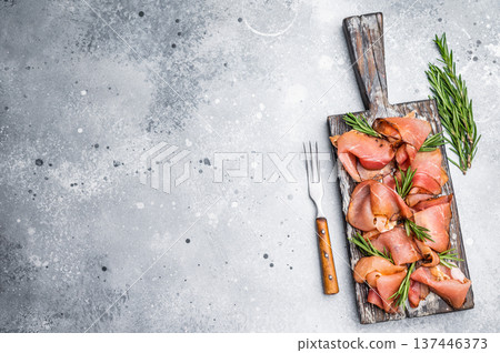 Italian Prosciutto ham, Parma ham on wooden board with rosemary. grey background. top view Italian Prosciutto ham, Parma ham on wooden board with rosemary. grey background. top view 137446373