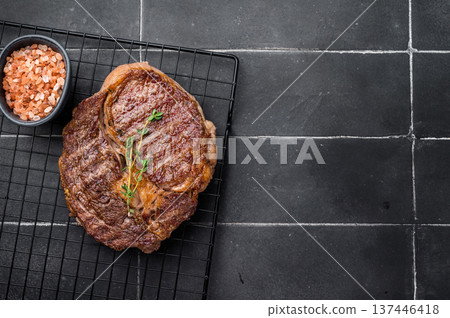 Grilled Rib eye steak on black rack, roasterd prime dry aged beef meat. black background. top view 137446418