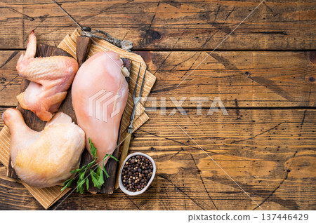 Fresh raw chicken from an eco farm, ready to be cooked.:A wooden cutting board holds three pieces of raw chicken Fresh raw chicken from an eco farm, ready to be cooked.:A wooden cutting board holds three pieces of raw chicken 137446429