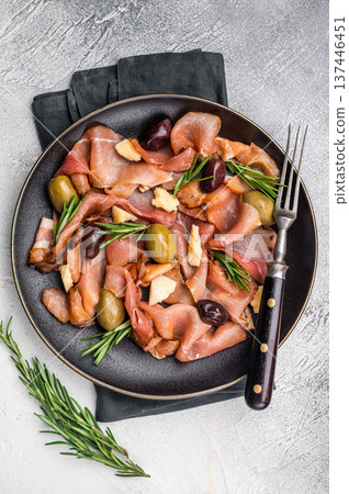 Antipasto with Prosciutto ham, parmesan cheese, rosemary and olives in a plate. grey background. top view Antipasto with Prosciutto ham, parmesan cheese, rosemary and olives in a plate. grey background. top view 137446451