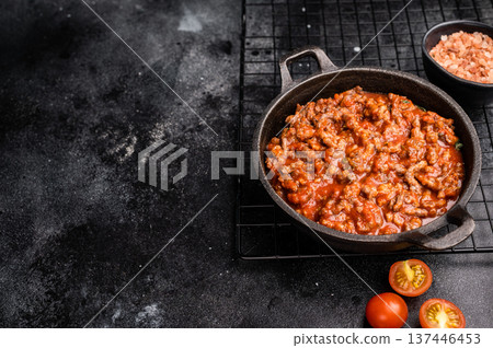 Bolognese sauce with minced beef, tomato paste and herbs in a skillet. black background. top view Bolognese sauce with minced beef, tomato paste and herbs in a skillet. black background. top view 137446453