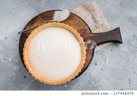 Versatile white sugar in a rustic bowl, ready to enhance desserts and beverages with its delightful sweetness. grey background. top view Versatile white sugar in a rustic bowl, ready to enhance desserts and beverages with its delightful sweetness. grey background. top view 137446476