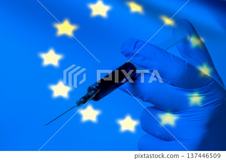 Blue gloved hand holds syringe against EU flag Blue gloved hand holds syringe against EU flag 137446509