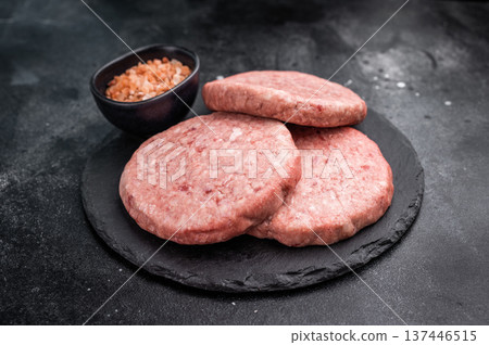 Fresh raw beef meat patty ready for grilling, perfect for homemade burgers and delicious family meals.black background. top view Fresh raw beef meat patty ready for grilling, perfect for homemade burgers and delicious family meals.black background. top view 137446515