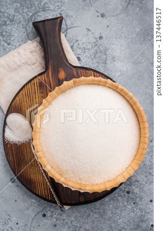Versatile white sugar in a rustic bowl, ready to enhance desserts and beverages with its delightful sweetness. grey background. top view Versatile white sugar in a rustic bowl, ready to enhance desserts and beverages with its delightful sweetness. grey background. top view 137446517