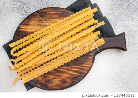 Delicate raw mafaldine pasta noodles, perfect for tossing with fresh ingredients and savory sauces. white background. top view 137446531