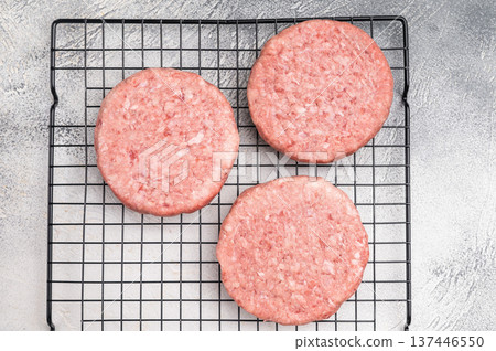 Close up of a juicy raw meat patty cutlet, ideal for crafting mouthwatering sandwiches and savory dishes. white background. top view 137446550