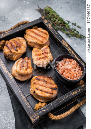 Tender char grilled pork medallion steak, perfect for adding a touch of elegance to your dinner plate.grey background. top view Tender char grilled pork medallion steak, perfect for adding a touch of elegance to your dinner plate.grey background. top view 137446587