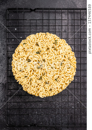 Raw instant ramen noodles, perfectly twisted and ready to be boiled for a delicious homemade soup. black background. top view Raw instant ramen noodles, perfectly twisted and ready to be boiled for a delicious homemade soup. black background. top view 137446589