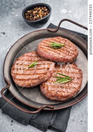 Close up of a flavorful grilled beef meat patty, ready to be topped with fresh ingredients for a delicious meal. grey background. top view Close up of a flavorful grilled beef meat patty, ready to be topped with fresh ingredients for a delicious meal. grey background. top view 137446593