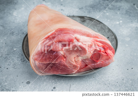 Uncooked pork shank hamhock with bone section, collagen fibers and skin layer arranged on plate with herbs ideal for butchery documentation. 137446621