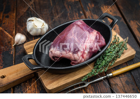 Raw heart used in pork cuisine placed on cast iron with thyme showing dense muscle fibers on rustic wood background. 137446650