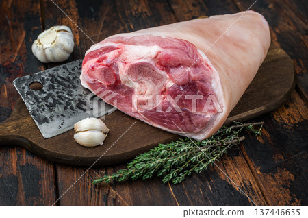 Raw pork knuckle with forged cleaver garlic and thyme on rustic wooden background perfect for butchery themes and recipe imagery. 137446655