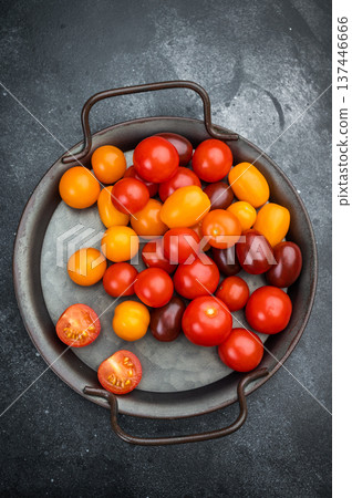 Colorful mix of cherry tomatoes in red yellow and orange tones arranged on a metal plate top view perfect for fresh cooking themes. 137446666