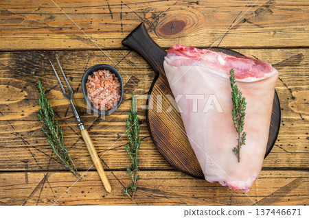 Raw pork knuckle hock with rind bone and muscle fibers on rustic board with thyme salt and meat fork ideal for butchery prep and culinary detailing. 137446671