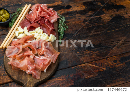Gourmet charcuterie platter featuring Italian salumi, cheese cubes, olives and breadsticks arranged on a wooden background. Gourmet charcuterie platter featuring Italian salumi, cheese cubes, olives and breadsticks arranged on a wooden background. 137446672