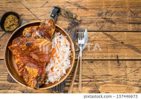 Crispy roasted pork knuckle shank with golden crackling rind served with fermented cabbage slaw on rustic wooden background. 137446673