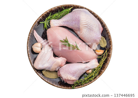 Raw chicken cuts: breast, wing, and drumsticks, seasoned with rosemary, thyme, and garlic on a dark ceramic plate. 137446695