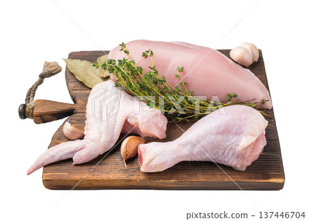 Raw chicken cuts: boneless breast, wing, and drumstick on a rustic wooden cutting board. Fresh poultry meat, high angle view. Raw chicken cuts: boneless breast, wing, and drumstick on a rustic wooden cutting board. Fresh poultry meat, high angle view. 137446704