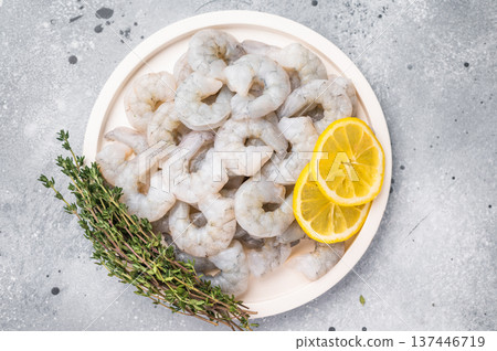 Fresh prawn shrimp tails on a wooden board. Gourmet ingredient with spices and lemon slices, ready for cooking on a rustic table. 137446719