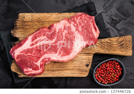 Uncooked Raw Chuck eye roll steak, prime beef meat on wooden board. black background. top view 137446726
