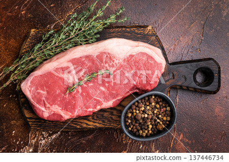 Raw New York strip beef steak, also named Striploin steak on a wooden board. brown background. top view 137446734