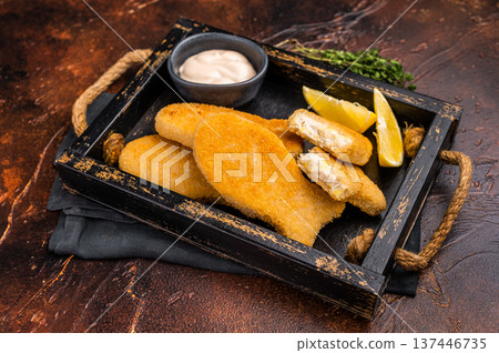Crusted Fish sticks fingers with lemon and tartar sauce in wooden tray. brown background. top view Crusted Fish sticks fingers with lemon and tartar sauce in wooden tray. brown background. top view 137446735