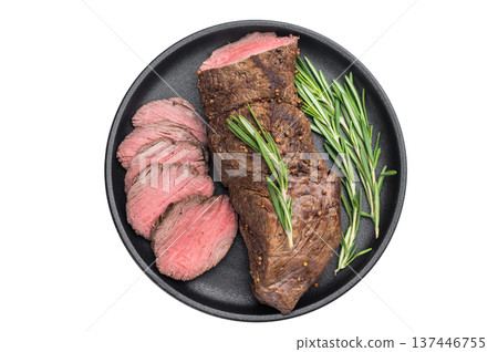 Medium rare roast beef cooked whole and sliced with rosemary. Juicy roasted beef tenderloin served in cast iron pan on white background. 137446755