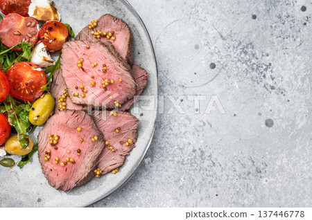 Gourmet beef roast sliced medium rare with Mediterranean salad on ceramic plate light background overhead food photo Gourmet beef roast sliced medium rare with Mediterranean salad on ceramic plate light background overhead food photo 137446778