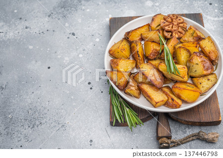 Crispy baked potato chunks with skin, rosemary and garlic. Homemade vegetarian food on wooden board Crispy baked potato chunks with skin, rosemary and garlic. Homemade vegetarian food on wooden board 137446798