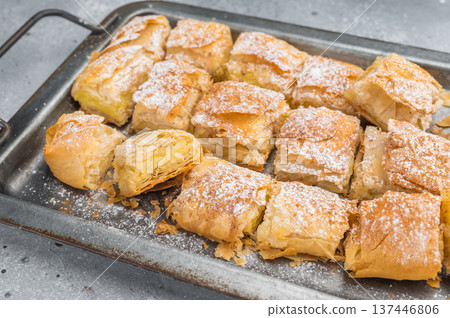 Traditional bougatsa Greek custard pastry with creamy milk filling flaky filo layers and powdered sugar bakery dessert Traditional bougatsa Greek custard pastry with creamy milk filling flaky filo layers and powdered sugar bakery dessert 137446806
